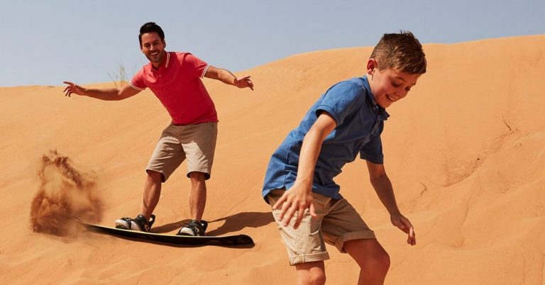 Dubai çöl safarisinde kum tepelerinde sandboarding yapan iki çocuk