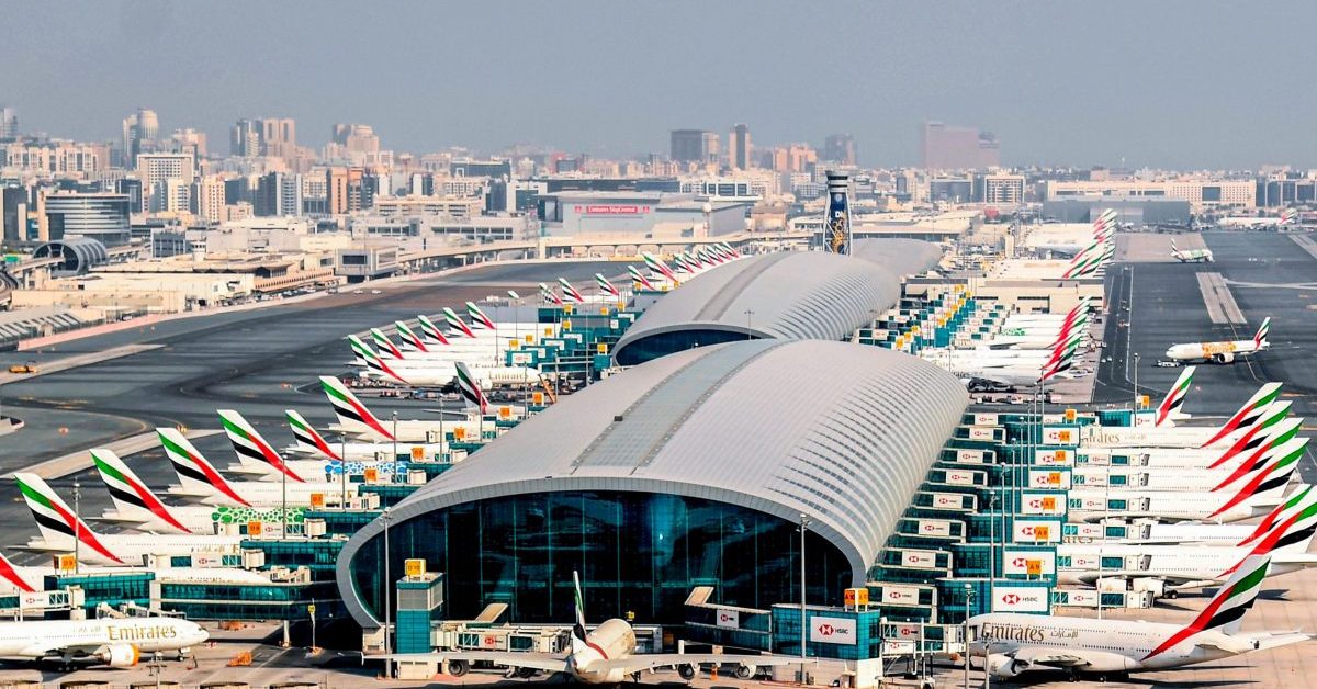 Çok sayıda Fly Dubai ve Emirates uçağının park halinde olduğu, arka planda şehir silüetinin görüldüğü Dubai Uluslararası Havalimanı'nın kuş bakışı görünümü.